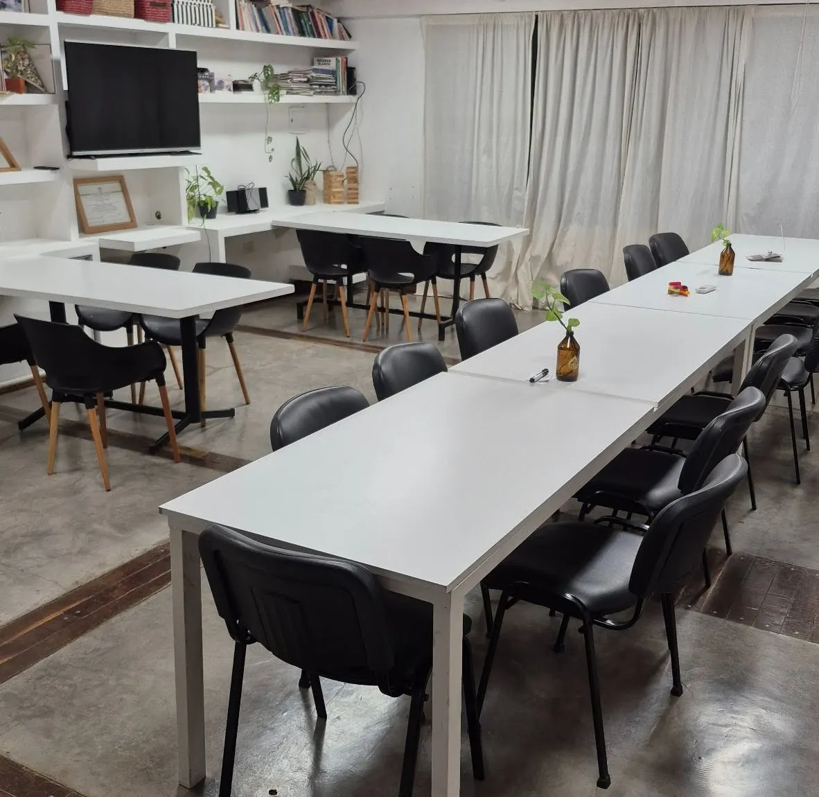 Salón Albricias con mesas largas blancas, televisor y estanterías